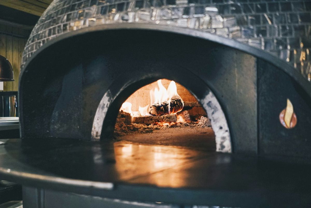 Tiled dome pizza oven with a log fire burning inside the arched opening